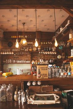 an old fashioned bar with lots of bottles and glasses on the shelves, along with lights hanging from the ceiling