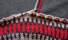 a knitted sweater with red and black stripes on it, next to a pair of scissors