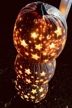 two lighted pumpkins sitting in the grass