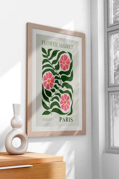 a flower market poster hangs on the wall next to a vase with flowers in it