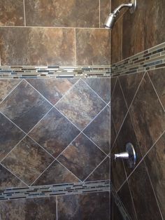 a tiled shower stall in a bathroom with brown tile walls and flooring, along with a chrome faucet