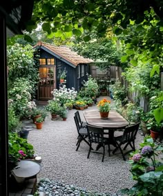 an outdoor dining table surrounded by potted plants and flowers in a garden with a shed behind it