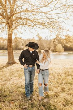 a man and woman standing next to each other under a tree