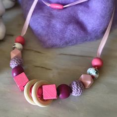 a necklace made out of wooden beads on a table next to a purple handbag