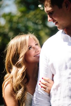 a man and woman standing next to each other with their arms around each other smiling