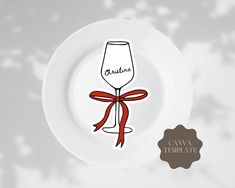 a white plate with a red ribbon around it and a wine glass sticker on the side