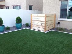 a backyard with artificial grass and potted plants