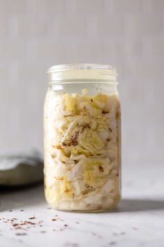 a glass jar filled with food sitting on top of a white counter next to a spoon