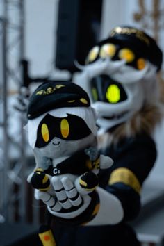 two stuffed animals dressed in black and yellow are posed with their hands on their hips