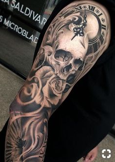 a man's arm with a clock and skull tattoo on the left side of his arm