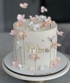 there is a white cake with pink and white flowers on the top that says elana