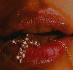 a woman's lips are adorned with gold chains and jewels as she looks at the camera