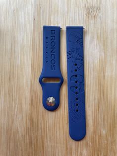 two blue watch bands sitting next to each other on a wooden surface, one has a metal buckle and the other has a rubber strap