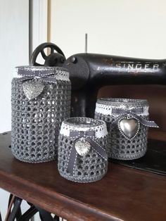 three jars are sitting on a table next to a sewing machine