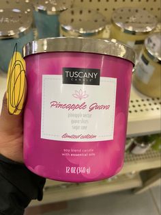 a person holding up a pink candle in a store