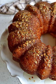 a bundt cake on a white plate with sprinkles and nuts around it