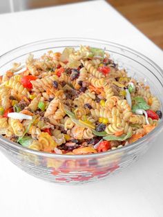 a glass bowl filled with pasta salad on top of a table