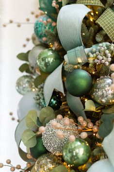 a christmas tree with green and gold ornaments on it's branches, bows and ribbons