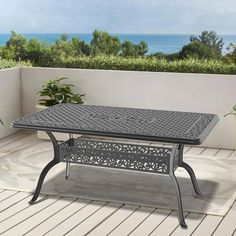 an outdoor dining table on a deck overlooking the ocean