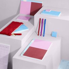 an assortment of stationery items displayed on white pedestals with pink and blue accents