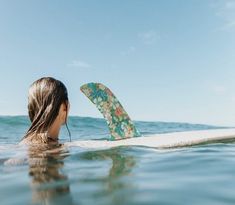 a woman is laying on her surfboard in the ocean looking at the sky and water