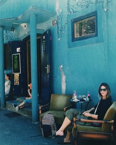 two women sitting on chairs in front of a blue building