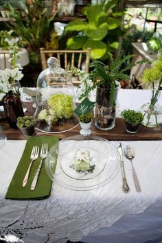 the table is set with silverware and flowers in glass vases on top of it