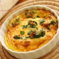 a dish with broccoli and cheese in it on a wicker place mat