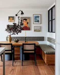 a dining room table with two chairs and a bench in front of the wall that has pictures on it