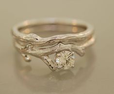 a white gold ring with a tree branch and a diamond