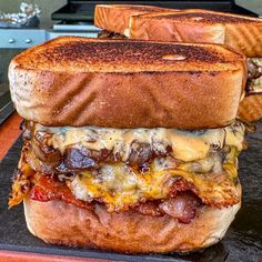 two sandwiches are stacked on top of each other, with cheese and meat in between them