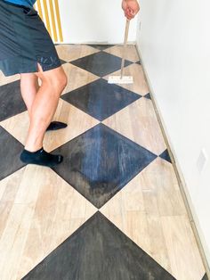 a man is painting the floor with black and white checkerboard pattern on it