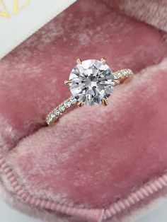 an engagement ring in a pink velvet box with the diamond set on it's side