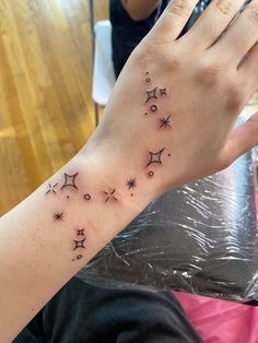 a woman's arm with stars and moon tattoos on it