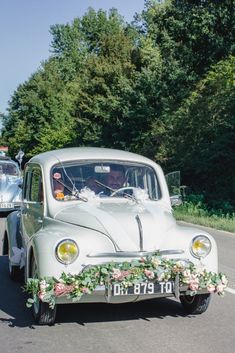 an old white car with flowers on the front