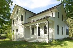 a large white house sitting on top of a lush green field