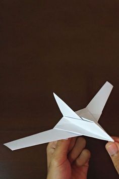 two hands are holding an origami airplane