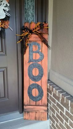 a wooden sign that says boo on the front door and is decorated with halloween decorations