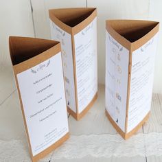 two folded menus sitting next to each other on top of a white tablecloth