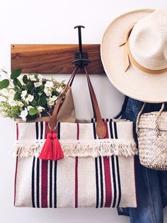 a hat, purse and flowers are hanging on a coat rack in front of a white wall