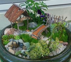 a potted planter filled with rocks, plants and small wooden houses in it