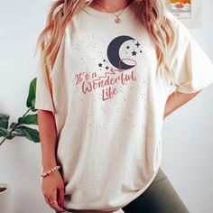 Get ready to be OBSESSED with your new Its a Wonderful Life shirt. It's the cutest and most trendy way to combine all those important trendy vintage and retro christmas vibes! This is the perfect holiday shirt!  * Q U I C K * F A C T S * ✺  All shirts are UNISEX ✺  100%  ringspun cotton (fiber content may vary for different colors) ✺  Soft-washed, garment-dyed fabric brings extra coziness ✺  Wash and dry normally (on cool for best results) ✺  Sewn-in twill label * S I Z I N G * ✺ For an oversized fit, select two or three sizes up from your normal size ✺ Model is wearing size L  ✺ Sizing runs true to size ✺ Relaxed fit ✺ Most women find their typical size works best, since they are meant to fit a touch loose ✺ See Size guide and fit in images          * S H I P P I N G * T I M E S * ✺ Our i Holiday Cotton Shirt With Crew Neck, Crew Neck Cotton Shirt For Holiday, Casual Cotton Tops For Holiday, Holiday Cotton Graphic Tee Shirt, Cotton Graphic Tee Shirt For Holidays, Cute Cotton Holiday Tops, Holiday Cotton Tops With Letter Print, Trendy Cotton Christmas Tops, Bedford Falls