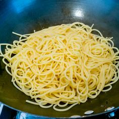 pasta being cooked in a wok on the stove