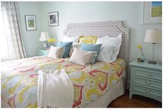 a bedroom with blue and yellow decor on the walls, white bedding, and green nightstands