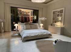 a bedroom with a large bed and two lamps on either side of the bed, in front of an open closet