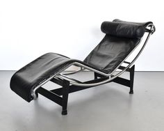 a black leather chaise lounge chair with chrome frame and footrests in front of a white wall