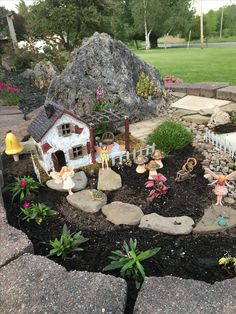 a small garden with fairy figurines in the middle and rocks on the ground