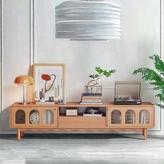 a living room with a wooden entertainment center and plants on the side table in front of it