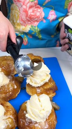 a person scooping ice cream onto doughnuts on a blue cutting board