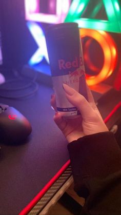 a person is holding up a cup in front of a computer desk with neon lights